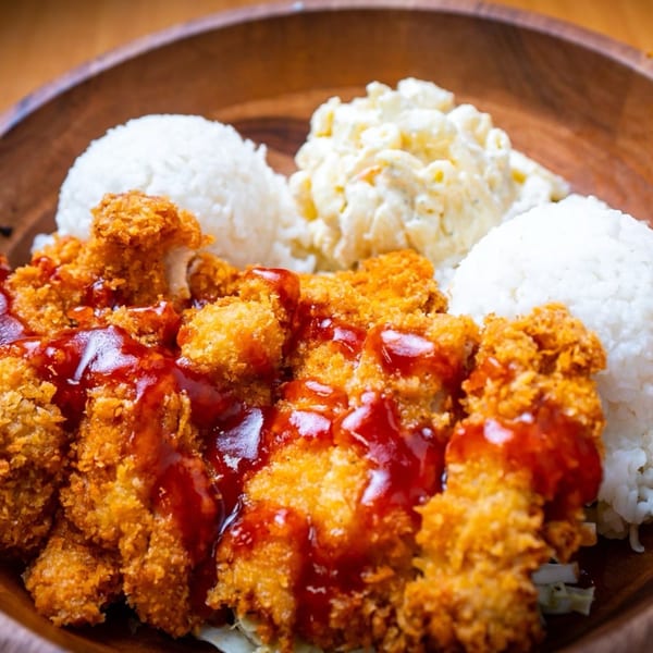 Crispy fried chicken with red sauce, white rice, and macaroni salad in a wooden bowl.