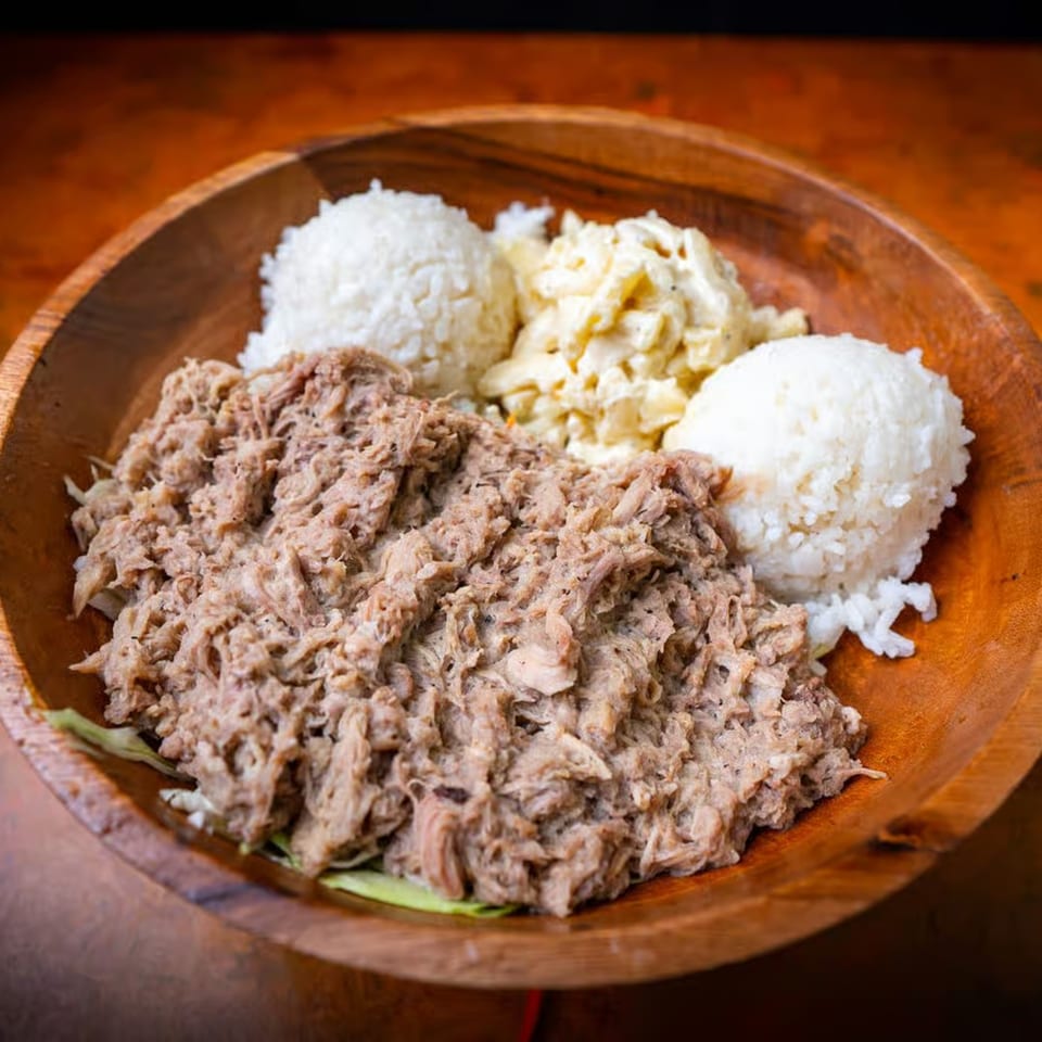 Hawaiian kalua pig with two scoops of white rice and macaroni salad in a wooden bowl.