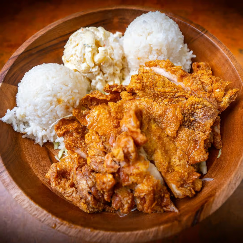 A wooden bowl filled with crispy fried chicken, two scoops of white rice, and macaroni salad.